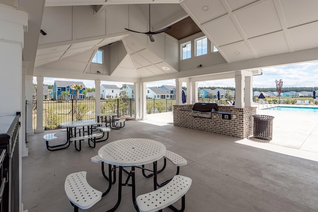 view of patio featuring a gazebo, fence, an outdoor kitchen, area for grilling, and a community pool