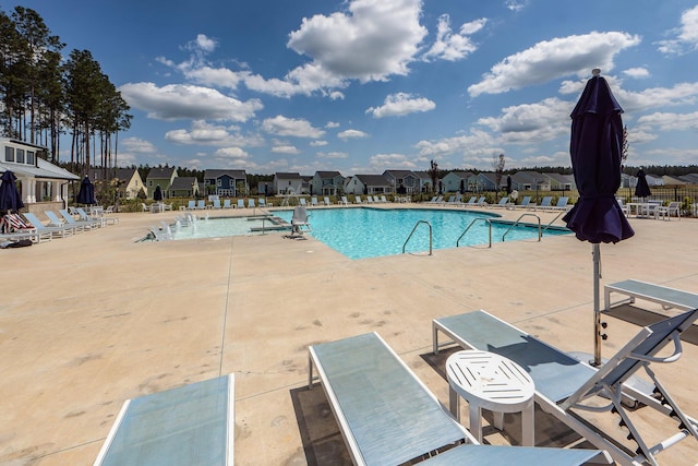 community pool featuring a residential view, a patio, and fence