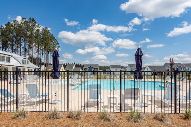 community pool featuring fence, a patio area, and a residential view