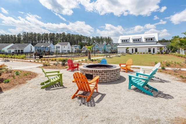 view of property's community with fence, a lawn, a fire pit, and a residential view