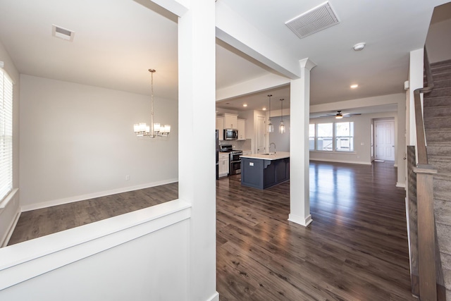 interior space featuring visible vents, a sink, dark wood-style flooring, and ceiling fan with notable chandelier