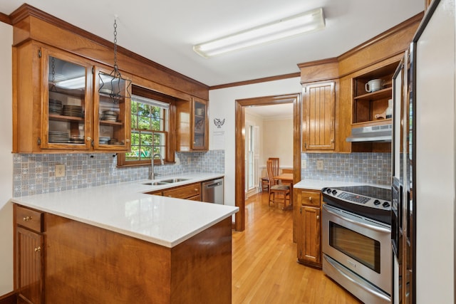 712 Wakendaw Blvd, Mount Pleasant, SC 29464 - kitchen with stainless steel appliances, under cabinet range hood, brown cabinets, light wood-style floors, and crown molding