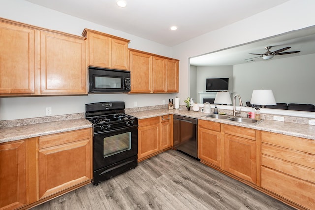 kitchen with black appliances, light wood finished floors, a sink, and light countertops