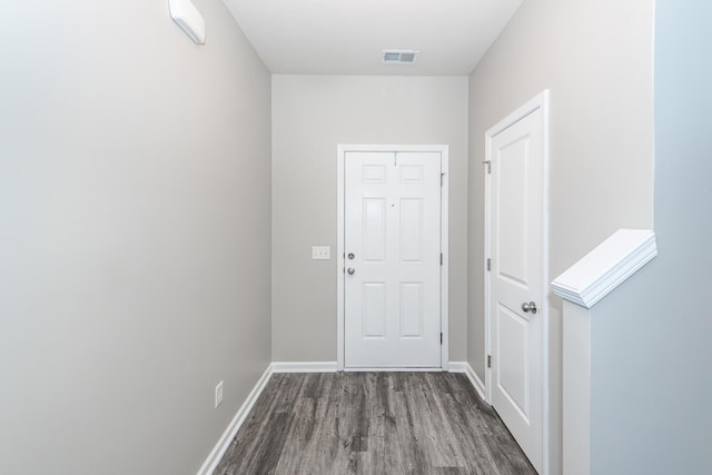 doorway with wood finished floors, visible vents, and baseboards