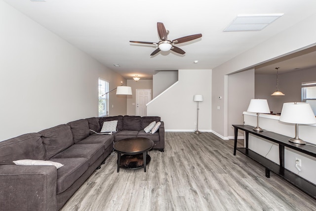 living area with a ceiling fan, baseboards, and wood finished floors