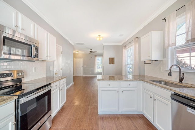 kitchen with kitchen peninsula, appliances with stainless steel finishes, ceiling fan, sink, and white cabinetry