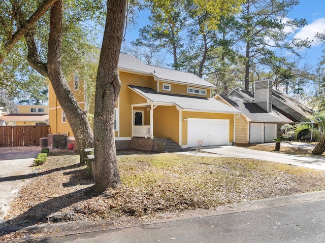 view of front of house with concrete driveway, central air condition unit, fence, and a garage