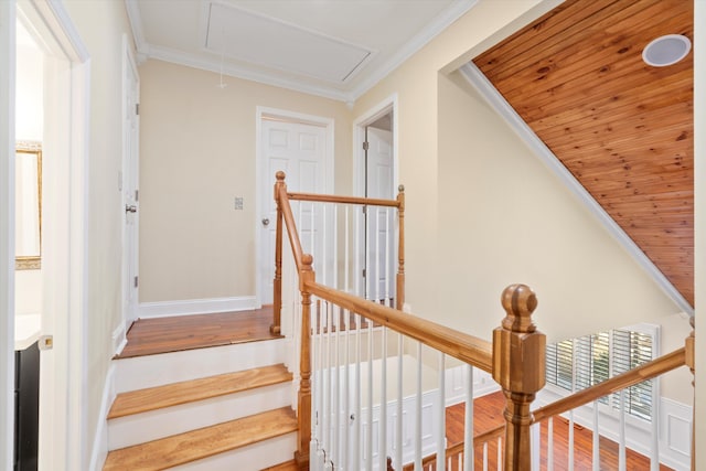 stairs featuring wood finished floors, attic access, baseboards, and ornamental molding