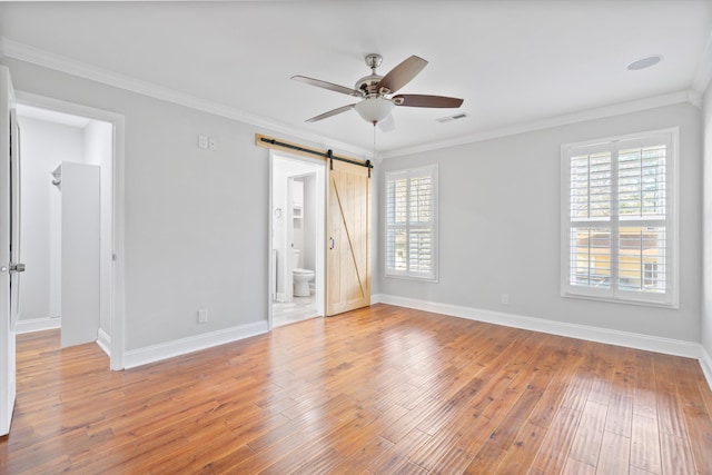 unfurnished room with visible vents, ornamental molding, a ceiling fan, wood finished floors, and a barn door