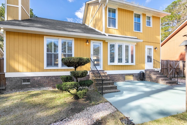 back of property with entry steps, a chimney, a shingled roof, and crawl space