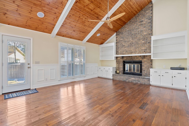 unfurnished living room featuring wainscoting, a brick fireplace, wood ceiling, and hardwood / wood-style flooring