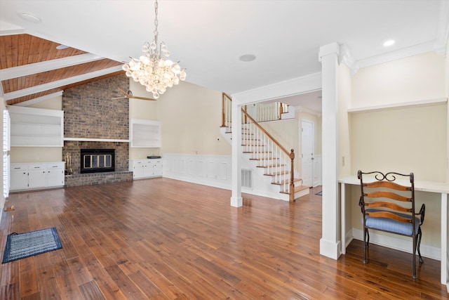 living area featuring visible vents, vaulted ceiling with beams, a fireplace, stairs, and wood-type flooring