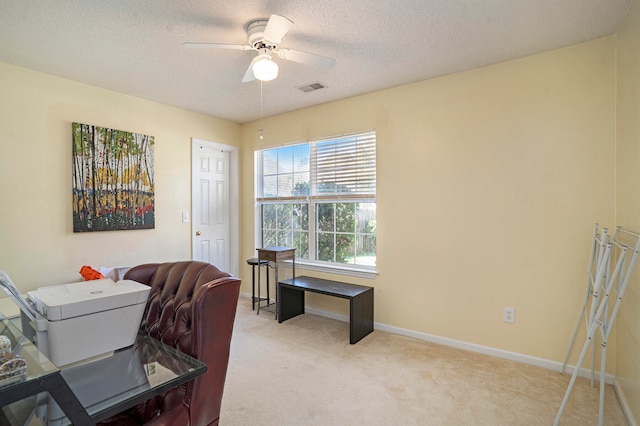 carpeted home office featuring a textured ceiling and ceiling fan