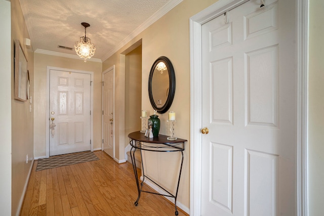 foyer with light hardwood / wood-style flooring, a textured ceiling, and crown molding