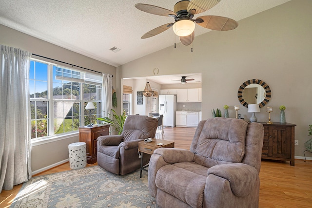 living room with light hardwood / wood-style flooring, a textured ceiling, ceiling fan, and vaulted ceiling