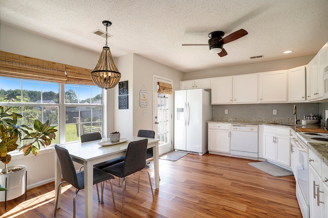 kitchen featuring light hardwood / wood-style flooring, white cabinets, hanging light fixtures, and white appliances