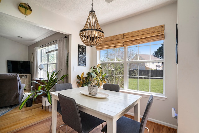 dining space with a notable chandelier, hardwood / wood-style flooring, and a textured ceiling