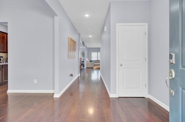 hallway featuring baseboards and dark wood-style floors