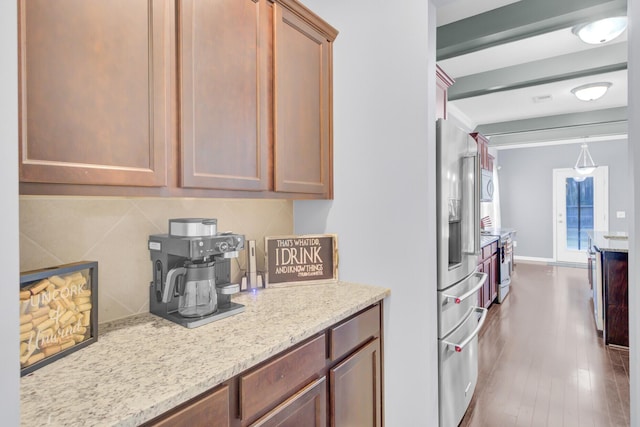 kitchen with stainless steel refrigerator with ice dispenser, backsplash, dark wood-style floors, baseboards, and light stone countertops