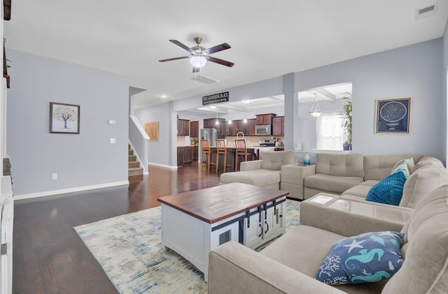 living room featuring baseboards, visible vents, dark wood-style flooring, ceiling fan, and stairs