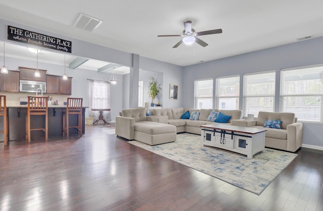 living room with baseboards, dark wood-style floors, visible vents, and ceiling fan