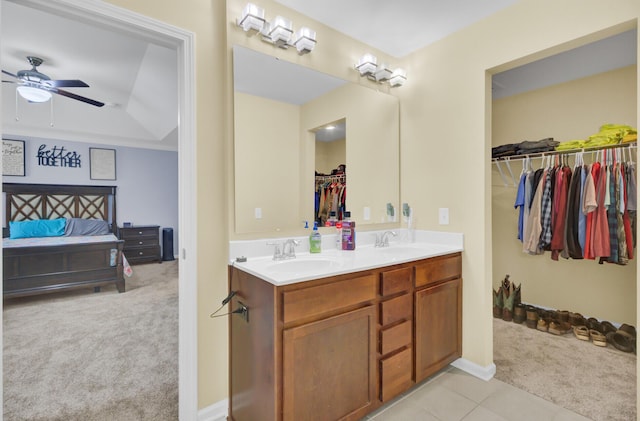 bathroom with a sink, a walk in closet, double vanity, and a ceiling fan