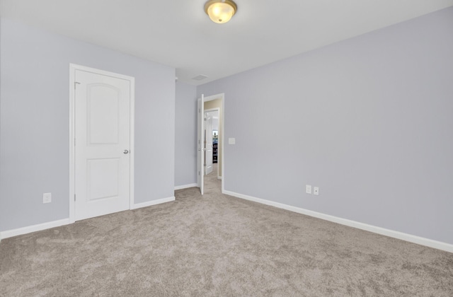 carpeted empty room featuring baseboards