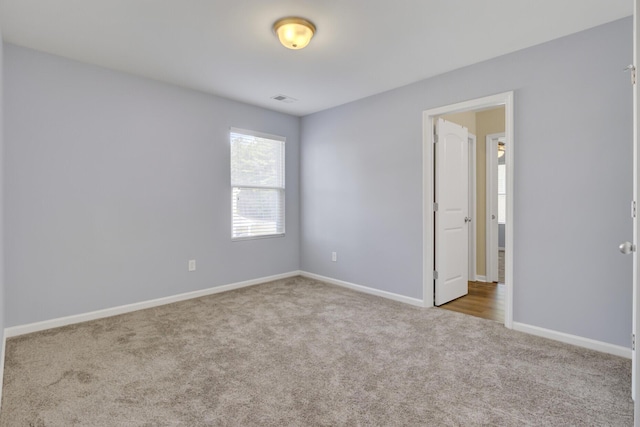 carpeted empty room featuring visible vents and baseboards