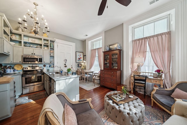 interior space with sink, dark hardwood / wood-style floors, pendant lighting, stainless steel appliances, and ceiling fan with notable chandelier