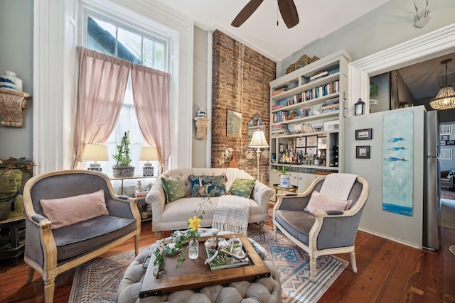 sitting room featuring ceiling fan, brick wall, and dark hardwood / wood-style flooring