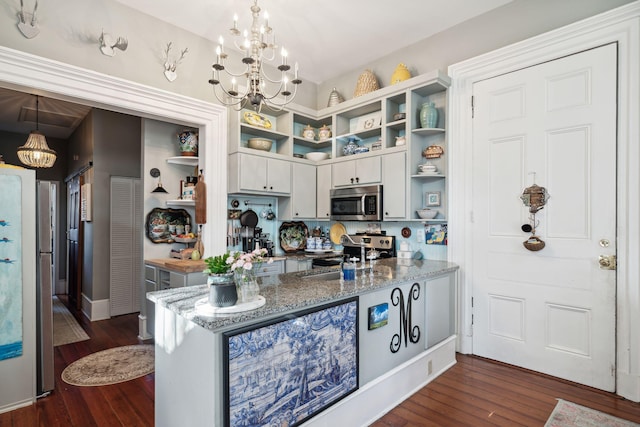 kitchen with dark stone counters, kitchen peninsula, white cabinets, and appliances with stainless steel finishes