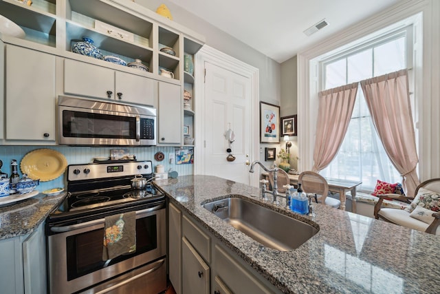 kitchen featuring plenty of natural light, stainless steel appliances, sink, and dark stone countertops