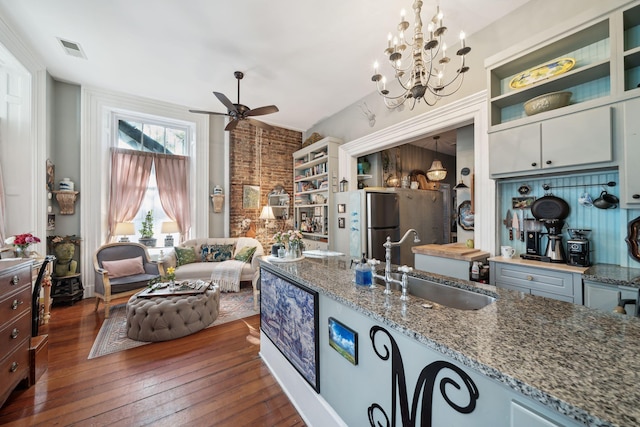 kitchen featuring dark hardwood / wood-style floors, stainless steel refrigerator, sink, hanging light fixtures, and light stone countertops