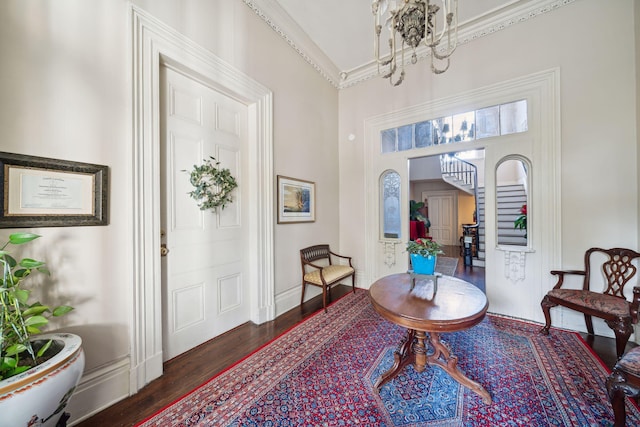 foyer with crown molding, dark wood-type flooring, and a notable chandelier