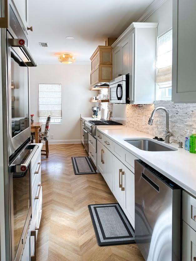 10 Riker St, Charleston, SC 29403 - kitchen featuring appliances with stainless steel finishes, light countertops, backsplash, and crown molding