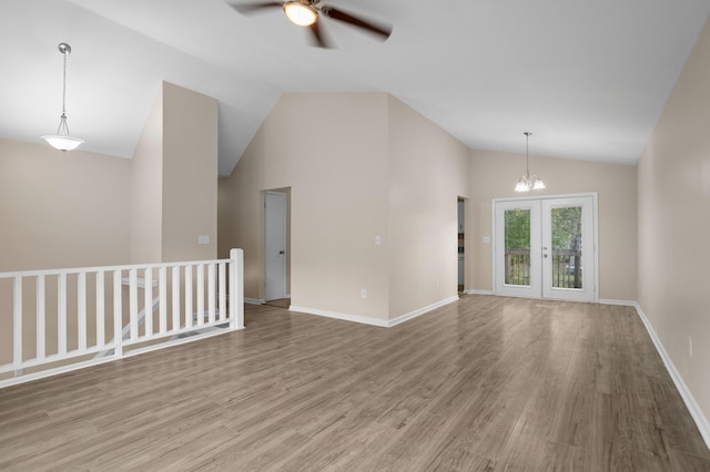 empty room featuring ceiling fan with notable chandelier, wood-type flooring, and high vaulted ceiling