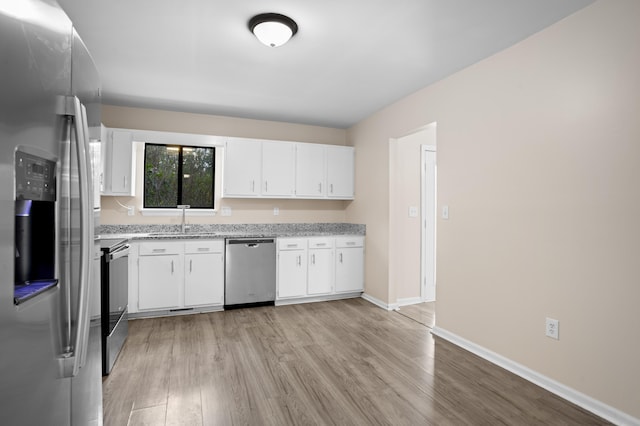 kitchen featuring sink, light hardwood / wood-style flooring, appliances with stainless steel finishes, light stone countertops, and white cabinets