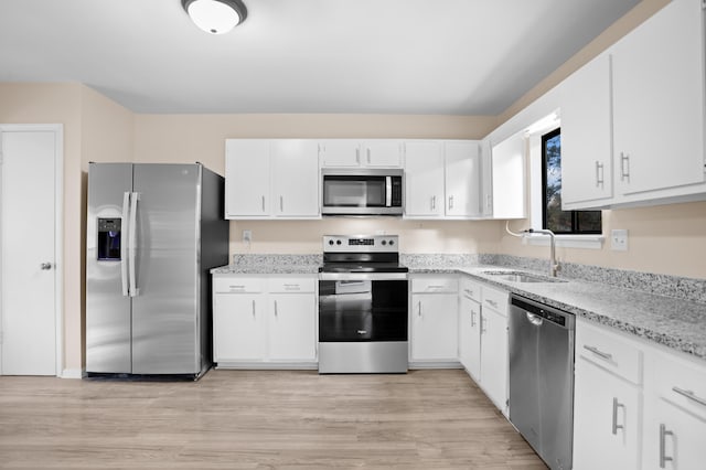 kitchen featuring white cabinetry, sink, light stone counters, stainless steel appliances, and light hardwood / wood-style flooring