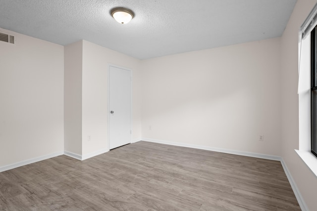 unfurnished room with light hardwood / wood-style flooring and a textured ceiling