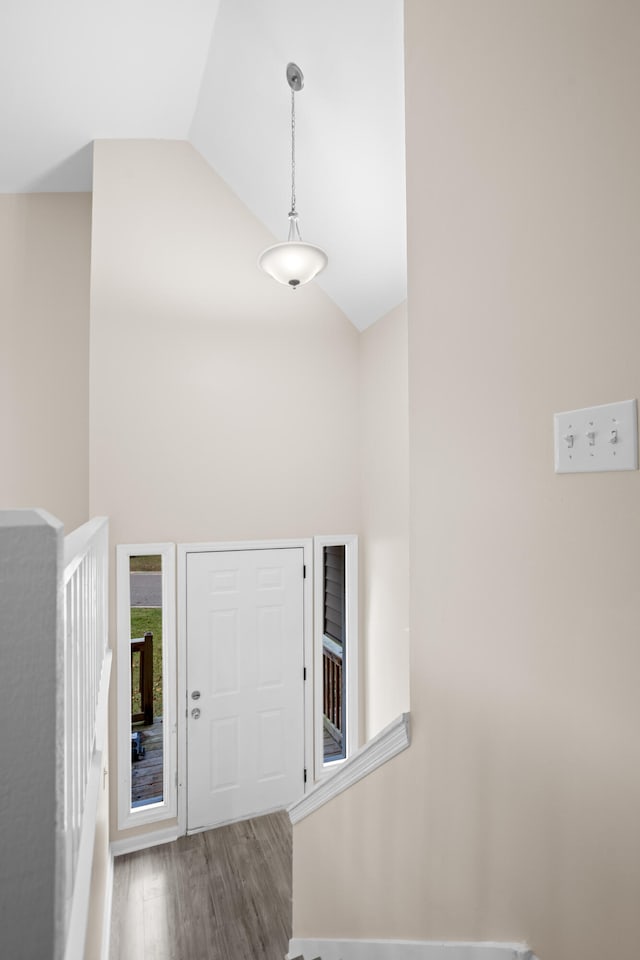 foyer entrance with wood-type flooring and high vaulted ceiling