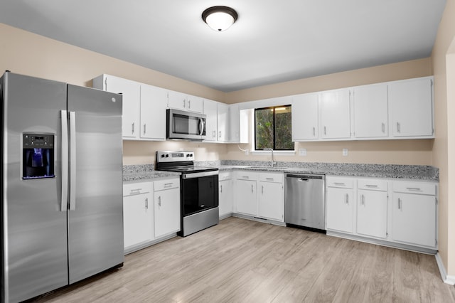 kitchen with stainless steel appliances, sink, white cabinets, and light hardwood / wood-style floors