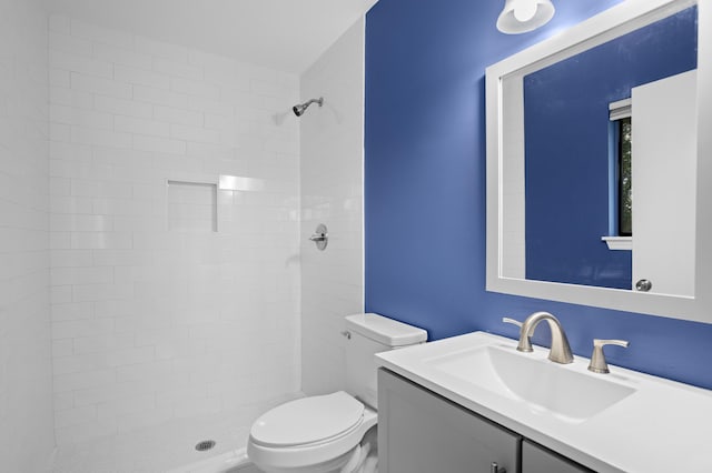 bathroom with vanity, toilet, and tiled shower