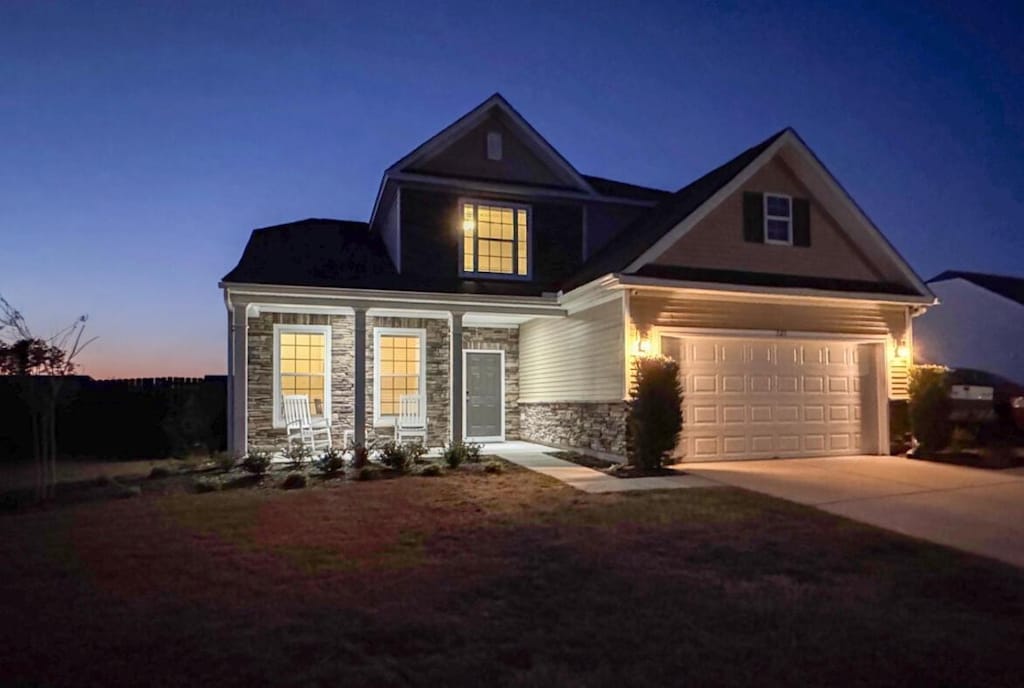 view of front of home featuring a garage, stone siding, and concrete driveway