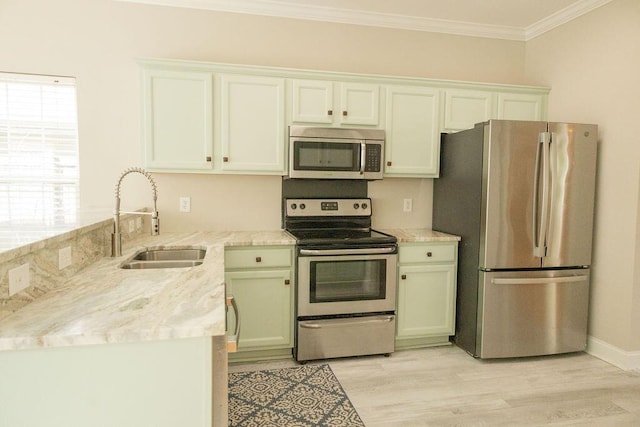 kitchen featuring crown molding, a sink, light wood-style floors, and stainless steel appliances