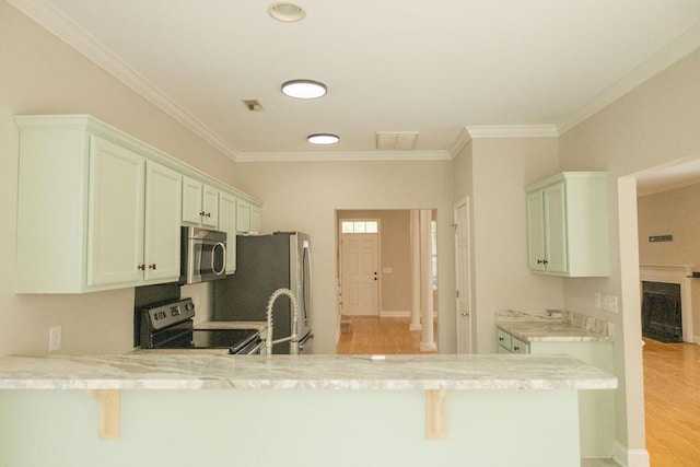 kitchen with crown molding, a peninsula, light wood-style flooring, and appliances with stainless steel finishes