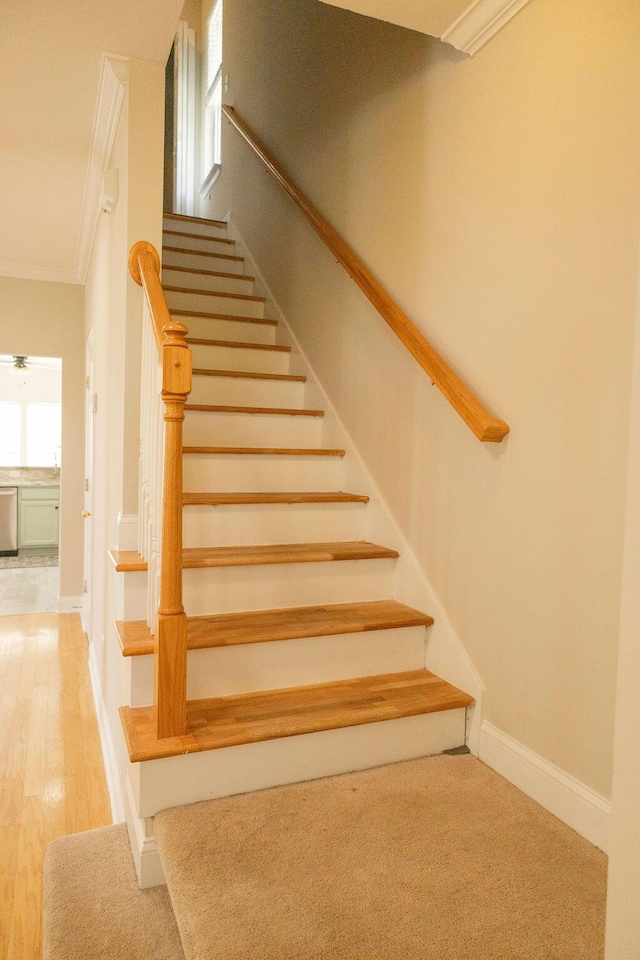 staircase with baseboards, ornamental molding, and wood finished floors