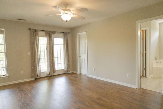 spare room with ceiling fan, plenty of natural light, and dark wood-type flooring