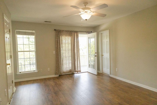 spare room with baseboards, a ceiling fan, wood finished floors, and a wealth of natural light