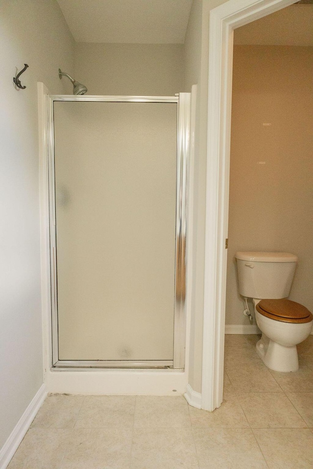 bathroom with baseboards, tile patterned flooring, a stall shower, and toilet