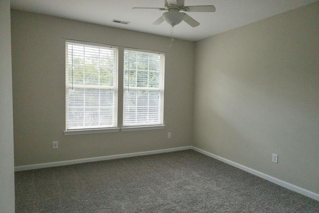 carpeted spare room featuring baseboards, ceiling fan, and visible vents